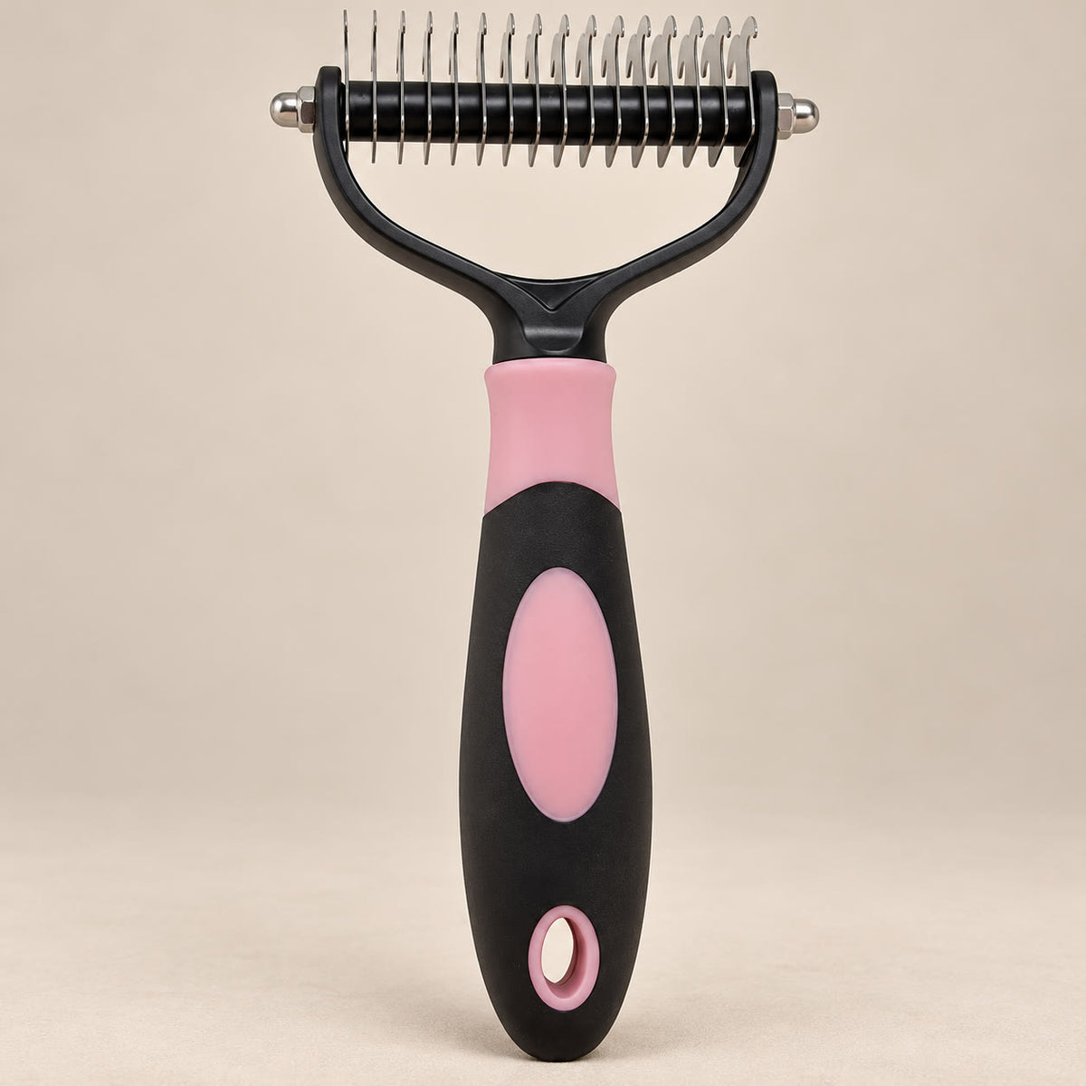 Pink double-sided pet grooming rake with stainless steel teeth - studio photograph on a warm neutral backdrop