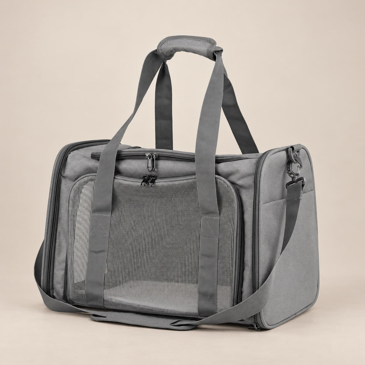 Grey soft pet carrier with mesh panels and shoulder strap - studio photograph on a warm neutral backdrop